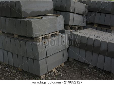 Stack of concrete curbstone. Construction process the dark one