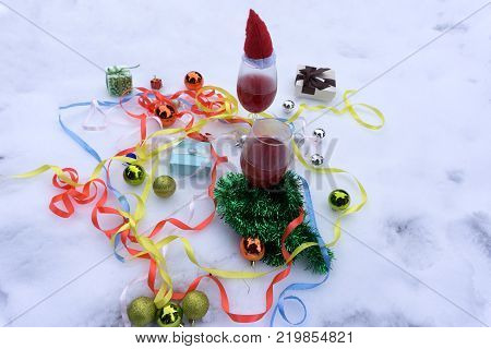 Two glasses with red wine on wooden table with fairylights and merry christmas card