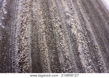 dirty melted snow and slush on the asphalt road in the winter season. photo close-up with a shallow depth of field