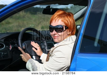 Red-Haired Woman In Sun Glasses In A Blue Car