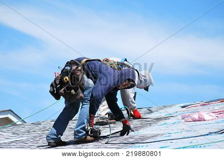 CASPER, WY. MAY 22, 2013. CIRCA: Male roofers at work outdoors on top of a housing project roof.