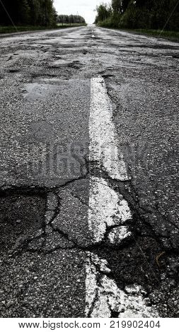 Bad asphalt road with white line.picture was made in Latvia