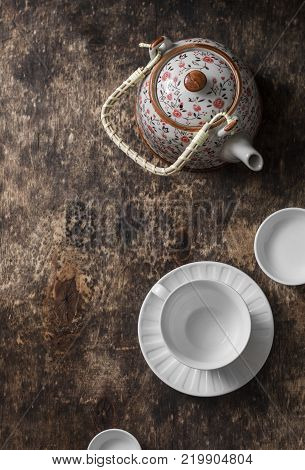 Tea set on a wooden table top view. Teapot empty white tea cup on a brown background top view. Free space for text
