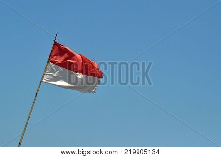 Indonesian flag fluttering below clear blue sky