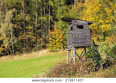 Wooden lookout tower for hunting in the woods and trees with colored leaves in autumn