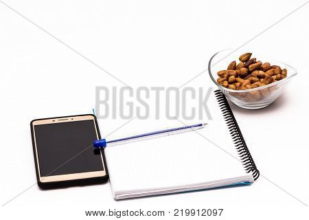 mobile phone and notebook on the desk with bowl of huzelnuts for keeping energy while working