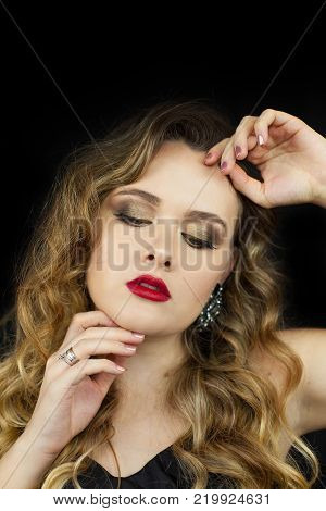 Portrait of a young beautiful woman with red lipstick on a black background. Makeup. Holidays.