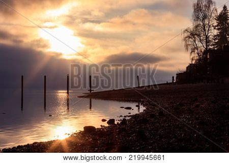glowy morning sunrise over calm reflective sound on rocky shoreline