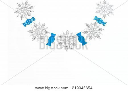 Decorative sparkly snowflakes and paper candies on white isolated background. Holiday new year garland top View Flat lay