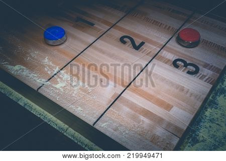 Vintage shuffle board game with red and blue disc on wooden shuffle table. Shuffleboard table game with selective focus.