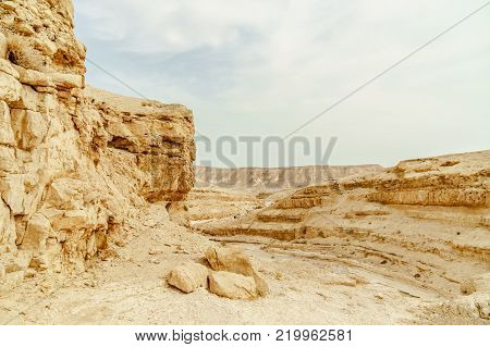Landscape of dry and wild desert in Israel. Valley of sand, rocks and stones in hot middle east tourism place. Scenic outdoor view on wild land. Summer heat and sunlight with nobody on photo