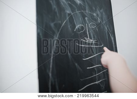 Cute little girl drawing on blackboard. Toddler girl having fun outdoors, holding chalk and drawing.