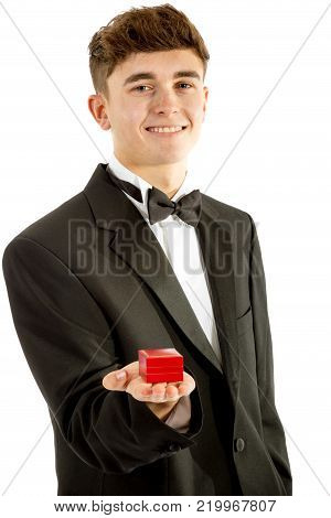 18 year old wearing a tuxedo smiling with a ring box isolated on a white background