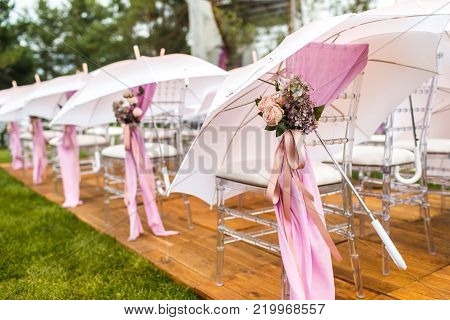 Chairs, flowers and umbrellas at an outdoor ceremony.