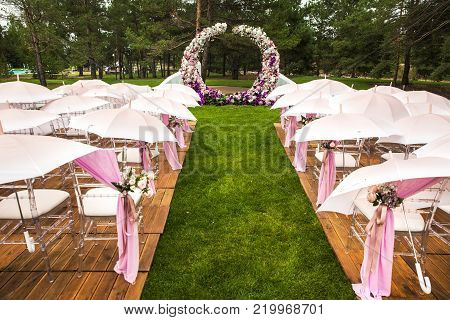 Outdoor wedding ceremony with umbrellas in the forest.
