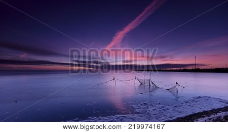 Fishnets in a calm and quiet blue sea under a blue and pink dawn