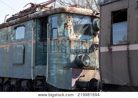 A rusty old green locomotive with brown car