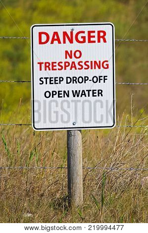 Danger no trespassing steep drop-off open water sign.