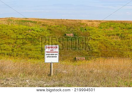 Danger no trespassing steep drop-off open water sign.