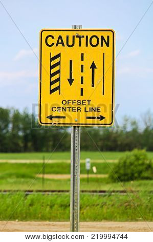 A caution offset center line road sign.