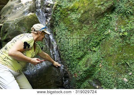Senior Woman Washing Herself With Water From Stream