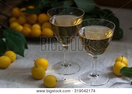 Cherry Plum Liqueur In Small Glasses And Cherry Plum On A Wooden Background. Rustic Style.