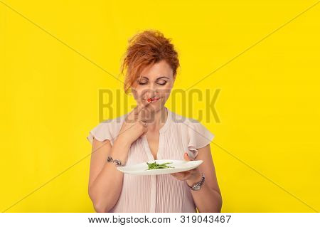 Unhappy Mature Woman With A Plate Of Green Salad Looking At It With Disgust Unhappy To Eat It, Think