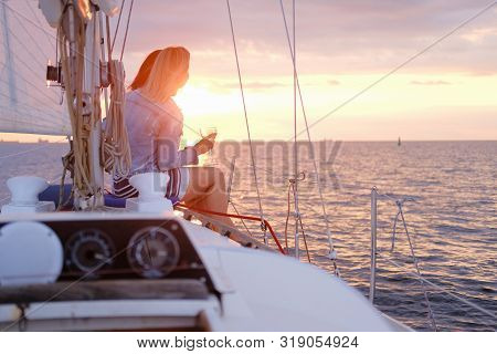 Two Joyful Women Are Celebraiting Good Summer Day At The Yacht While Watching Beautiful Sunset.