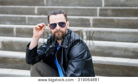 Fashion Portrait Of Young Bearded Man. Handsome Hipster Guy Posing In Sunglasses