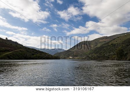 Scenic View Of The Douro River With A Traditional Rabelo Boat And Terraced Vineyards Near The Tua Vi