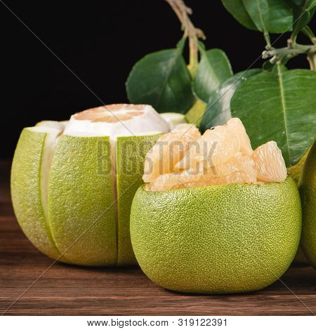 Fresh Peeled Pomelo, Grapefruit, Shaddock With Green Leaves On Dark Wooden Plank Table. Seasonal Fru