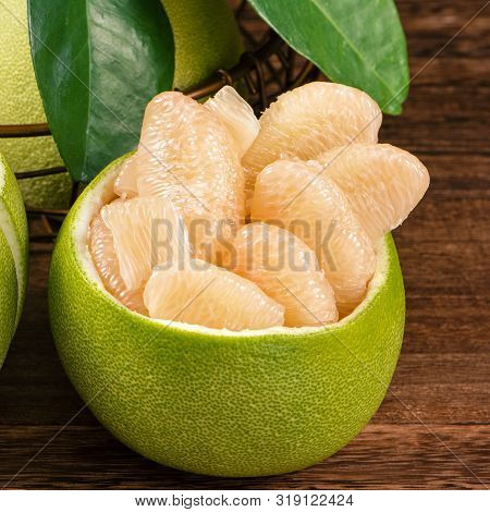 Fresh Peeled Pomelo, Grapefruit, Shaddock With Green Leaves On Dark Wooden Plank Table. Seasonal Fru