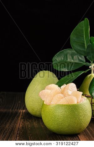 Fresh Peeled Pomelo, Grapefruit, Shaddock With Green Leaves On Dark Wooden Plank Table. Seasonal Fru