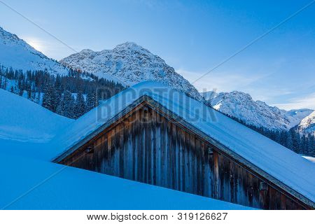 Alpine Cottage In Swiss Alps Near Arosa Covered By Snow In Winter, Blue Sky