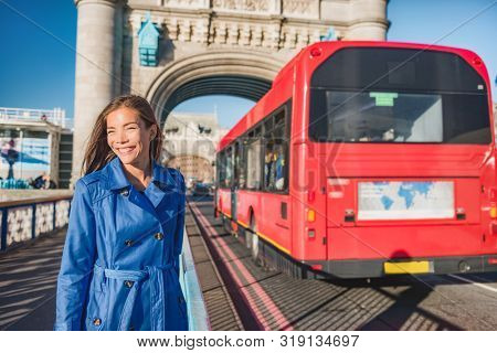 London woman walking commute on Tower Bridge city street using public transport bus commuting in the morning. Happy young Asian british business worker going to work or tourist city travel.