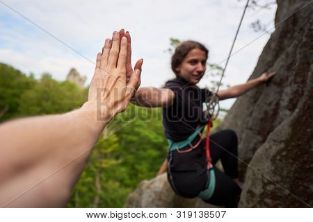 Young Female Rock Climber Hanging On Safety Harness And Rope. Man Helping His Friend And Climbing Ro