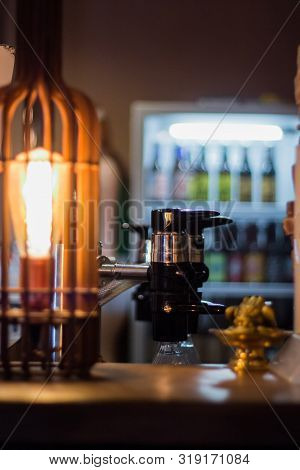 Pouring Beer On A Tap In A Bar Pub Before Octoberfest With A Cozy Lamp Light.