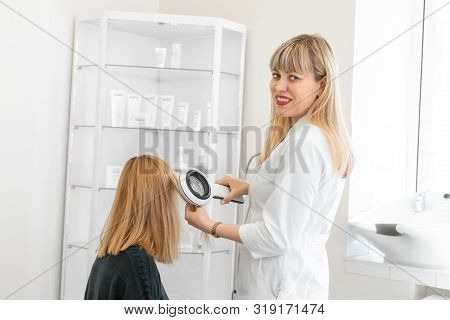 Physician Trichologist Dermatologist Examines The State Of The Patient's Hair And Hair Roots With A 