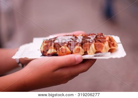 Hand Of A Girl Holding A Chocolate Waffle In A Street Of Ghent