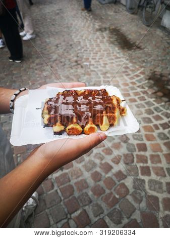 Hand Of A Girl Holding A Chocolate Waffle In A Street Of Bruges