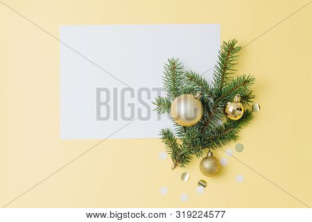 Happy New Year Composition. Paper Sheet, Fir Branch With Decorations Over Yellow
