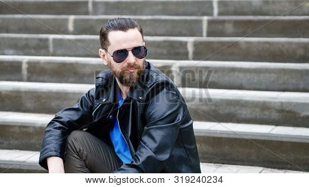 Fashion Portrait Of Young Bearded Man. Handsome Hipster Guy Posing In Sunglasses