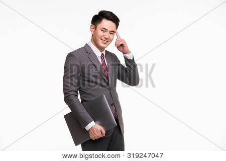 Smiling Handsome Asian Businessman Standing Point His Finger At His Head And Holding Notebook Comput