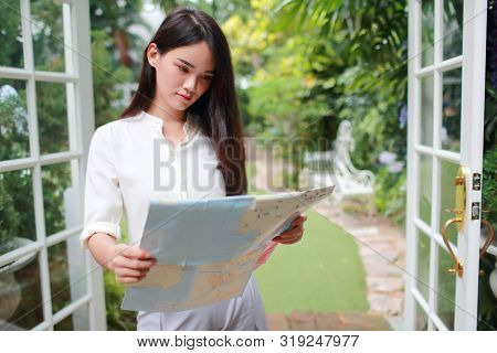 Young And Cute Asian Woman Searching Location In A Map During Holiday