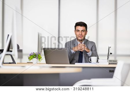 Handsome Caucasian Businessman Holding A Pen In His Hands, On A Table With A Notebook And A Coffee M