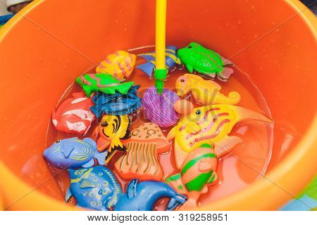 Fishing In The Paddling Pool. Childrens Toys In The Pool. Toy Fish Fishing Rod. Cheerful Children Fi