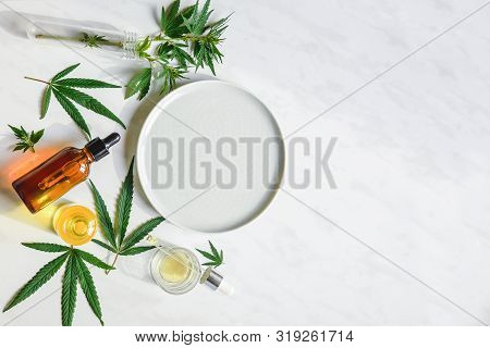 Various Glass Bottles With Cbd Oil, Thc Tincture And Hemp Leaves On A Marble Background. Copy Space,