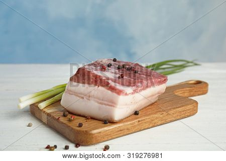 Board With Pork Fatback, Peppercorn And Onions On White Wooden Table