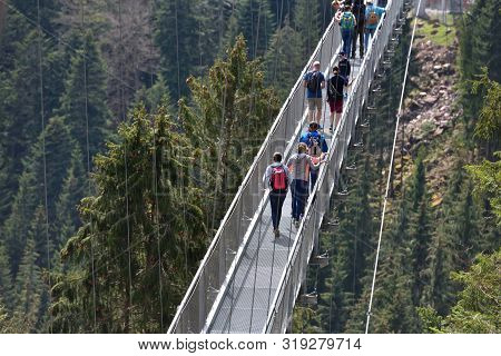 Bad Wildbad, Germany - April 22, 2019: Tourists Walk Along A Long And Suspended Iron Cable Bridge Fo