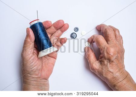 Senior Woman's Hands Holding Thread Roll, Needle, Button Isolated On White Background, About Tailor